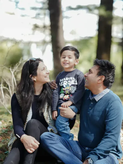A candid family moment in the woods. The natural smiles and loving gazes are what make outdoor photoshoots so special, capturing your family in a relaxed and authentic way.