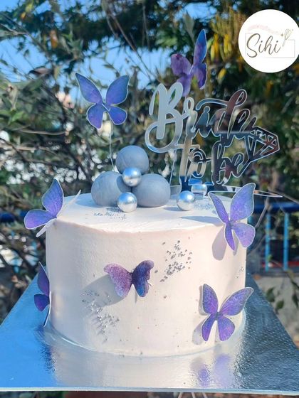 Fly me away. A "Bride to Be" cake with a dreamy, ethereal feel. The simple white cake is decorated with purple edible butterflies and silver baubles.