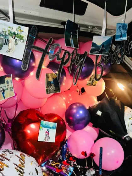 An overhead view of the birthday car boot decor, showing the 'Happy Birthday' sign, photos, and a large heart-shaped balloon.