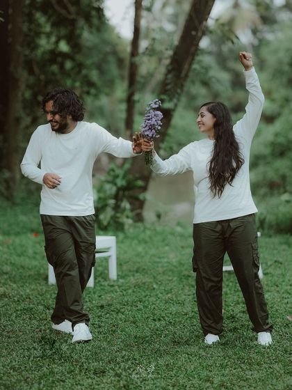 The couple dancing joyfully in a field, celebrating their love with energy and happiness.