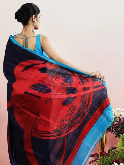 A stunning saree with an abstract print in shades of blue, red, and green. The pallu features a bold, artistic design.