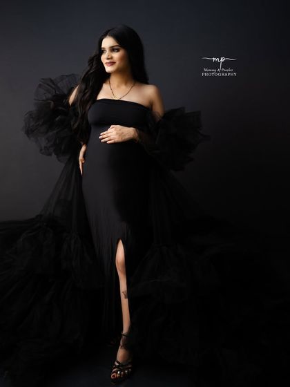 Stunning is the only word. This full-length shot shows off the dramatic black tulle gown, creating a high-fashion and glamorous maternity portrait.