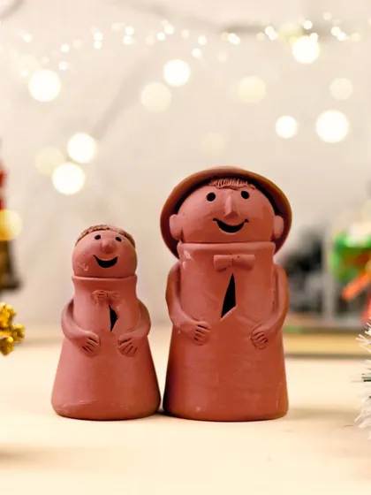 Bringing smiles to the season. These two adorable terracotta figurines are captured together, creating a heartwarming scene that adds a touch of handmade joy to any festive decor.