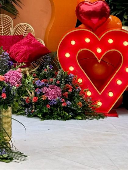 A detail shot of the large, illuminated heart prop and surrounding floral decor. Marquee lighting like this adds a warm glow and serves as a fantastic photo opportunity for guests.