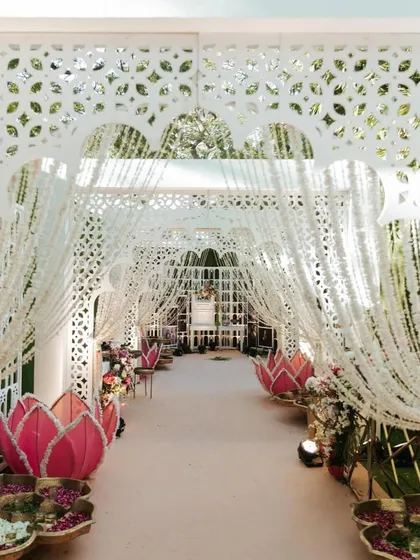 Another view of the enchanting walkway to the Lotus Mandap. The intricate white jaali arches and hanging flower strings create a beautiful, layered tunnel effect for guests to walk through.