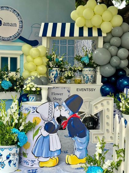 A unique and charming Dutch theme for a first birthday, featuring a flower shop stand, Delft blue patterns, and cutouts of a traditional Dutch couple. This shows my ability to create highly customized and imaginative party setups.