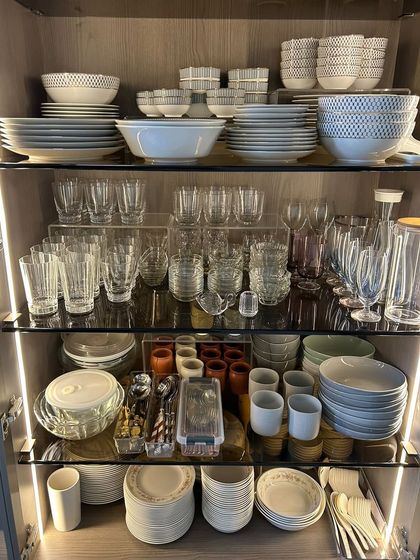 A fully stocked crockery cabinet, organized for a large family or someone who loves to entertain. Every glass, plate, and bowl is grouped by type for easy access.