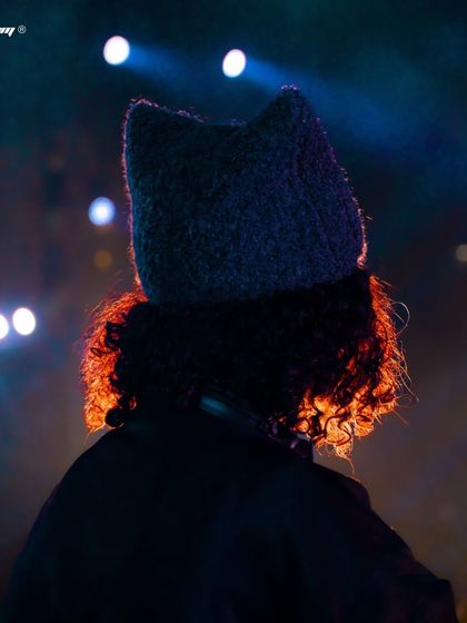 A shot from behind DJ Carlita, with the stage lights creating a beautiful rim light effect on her hair.