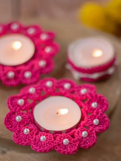 Bright pink crochet diya coasters embellished with small pearls. This design combines traditional elements with a fun, modern color for a unique festive look.