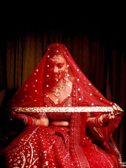 A classic bridal portrait under the veil. The rich red color and the delicate pearls on the veil create a timeless and romantic image.