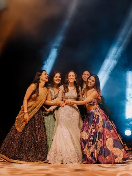 The bride surrounded by her best friends on the Sangeet stage. The dramatic lighting and their happy faces make this a perfect shot of friendship.