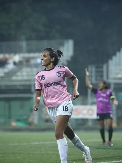 A player celebrating her goal with a smile, a picture of pure joy and accomplishment.