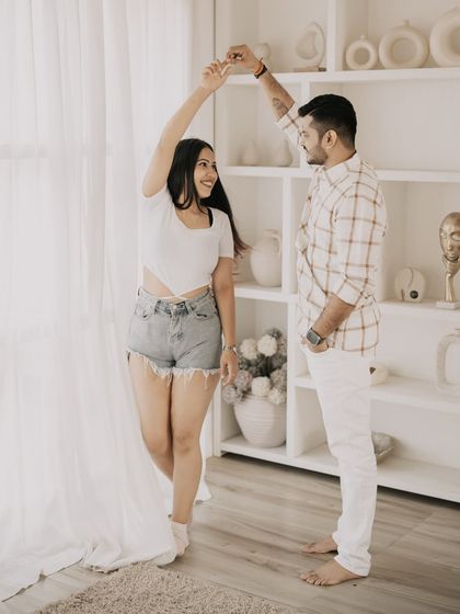 A candid moment of the couple dancing in a bright, minimalist studio space, showing their joyful connection.