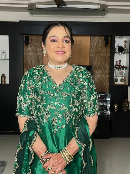 A happy client ready for a wedding celebration. She is wearing a beautiful green outfit, and her makeup is soft and glowing.
