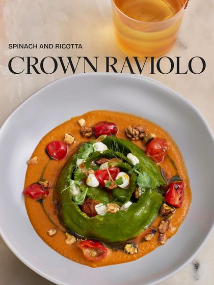 A closer look at the details of our Spinach and Ricotta Crown Raviolo. The vibrant green of the spinach pasta contrasts beautifully with the rich, orange-hued tomato and miso sauce.