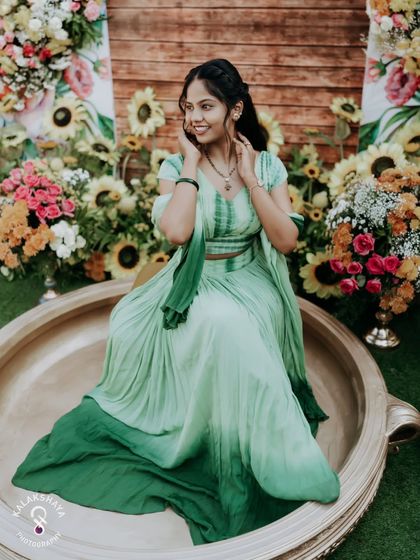 A stunning portrait of the bride during her Haldi ceremony, seated in a giant decorative urli.