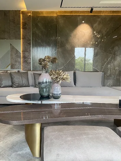 The beauty of our work is in the details. Here, a custom two-tiered coffee table, combining polished marble and rich wood, sits before a backdrop of our signature wall paneling. The interplay of textures and integrated lighting demonstrates our commitment to material excellence.
