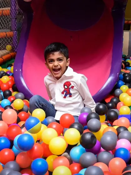 A huge, happy smile from a boy enjoying his time in the ball pit.