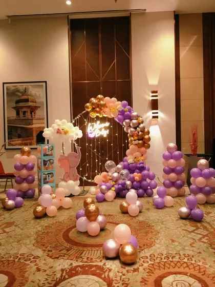 A full room view of a welcome baby party with an elephant theme, featuring a balloon ring and multiple balloon pillars.