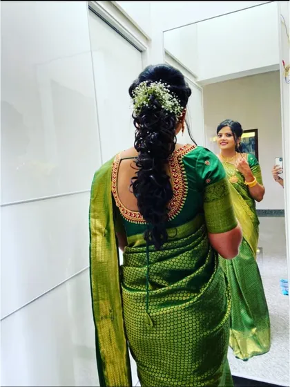 Here is an example of a modern hairstyle for a traditional outfit. This textured, curly pulled-back style is adorned with baby's breath, offering a contemporary yet elegant alternative to a classic braid.