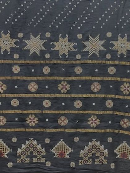 An advanced Kasuti pattern on a dark fabric, showcasing star and floral motifs. The use of metallic and colored threads adds a subtle richness to the design.