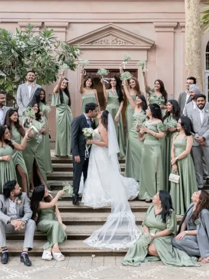 A picture-perfect moment with the entire bridal party on the steps of the venue. The coordinated outfits and the couple's central kiss create a stunning and memorable group portrait.