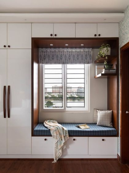 This charming bay window includes a cozy reading nook with built-in storage drawers underneath, a perfect example of multi-functional design.