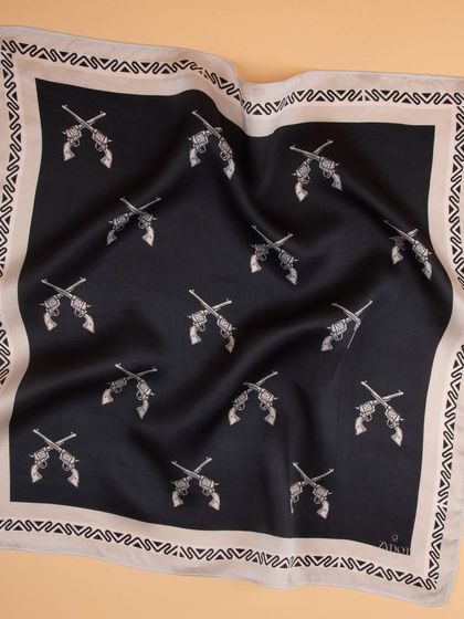 A draped shot of a black pocket square with a repeating crossed-pistols print, showing fabric quality.