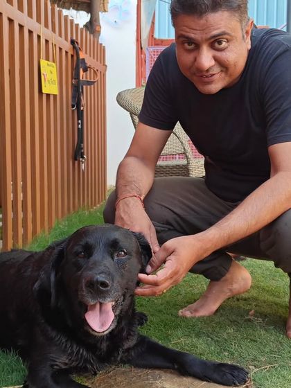 A pet parent shares a moment with his black Labrador. We love seeing the strong bonds between owners and their dogs at our facility.