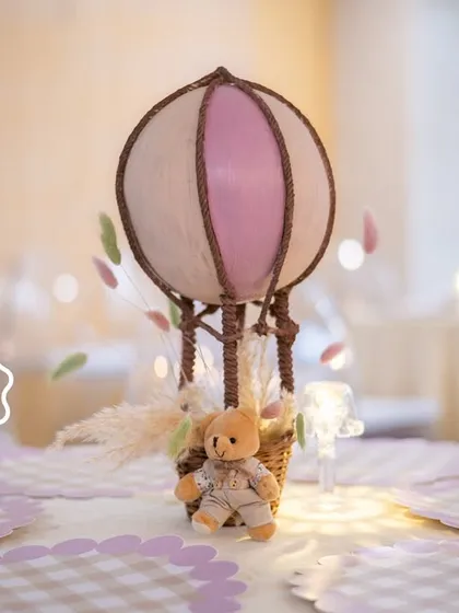 A beautifully composed shot of the hot air balloon centerpiece, capturing the dreamy and gentle atmosphere of the baby shower.