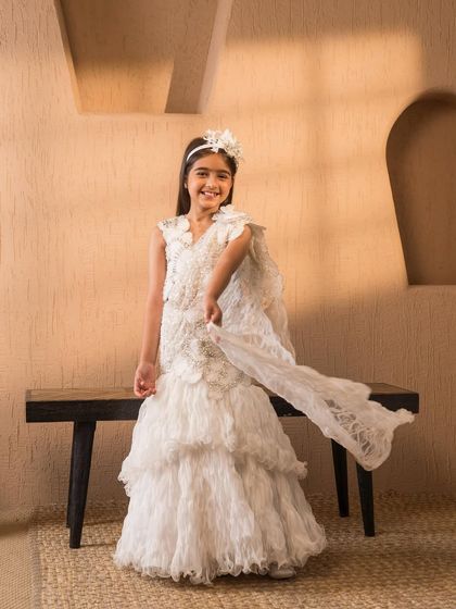 The lightweight, ruffled layers and pre draped dupatta make this white lehenga both beautiful and easy for a child to wear.