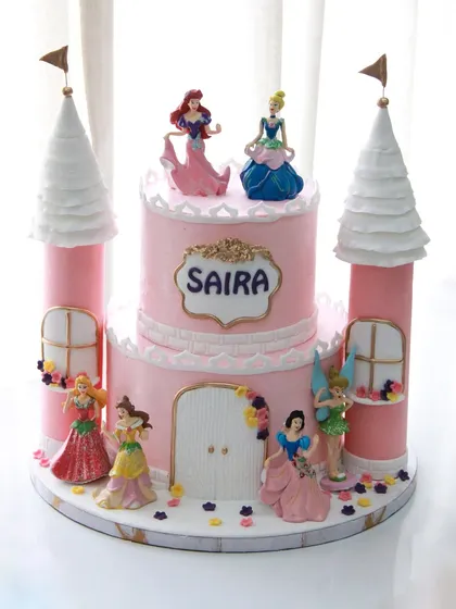 A princess castle cake fit for royalty. This cake for Saira's 3rd birthday features multiple Disney princesses around a beautiful pink castle with towering turrets.