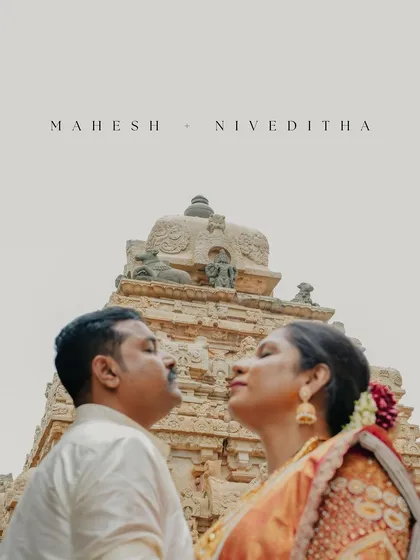 A beautifully composed 'Save the Date' style photo. The couple is framed perfectly under the temple's gopuram, creating a culturally rich and personally significant image.