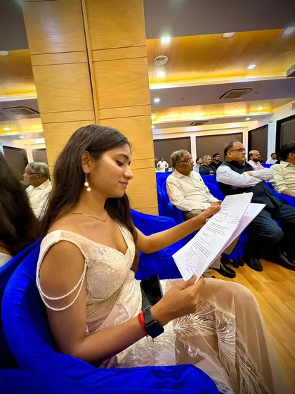 Here I am seated and reviewing my notes during an event. It's crucial to be prepared, but also to stay relaxed and confident to maintain a great stage presence.