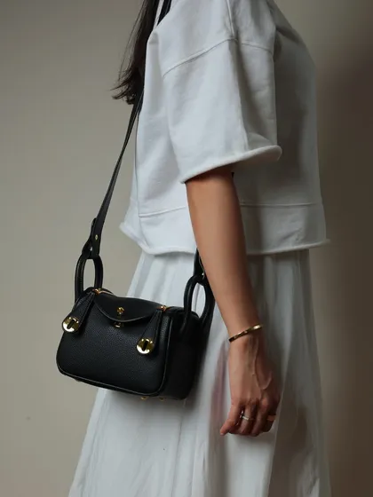 The Linde Mini in black, showing off its pebbled leather texture and shiny gold hardware. It's a timeless piece that you can easily dress up or down.