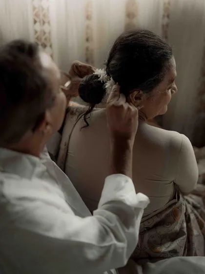 A close up of a loving gesture. The act of him helping her with her hair is a small detail that speaks volumes about their partnership and care for one another.