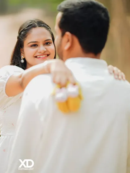 A creative and intimate shot with the focus on the baby shoes held behind the father-to-be's back.