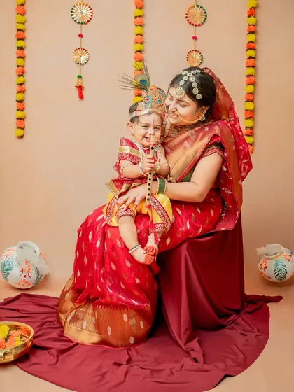Yashoda and Krishna sharing a happy moment together. The mother is dressed in a beautiful saree that complements the theme.