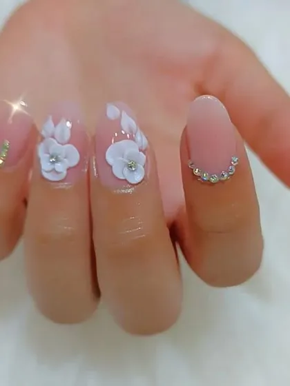 A close-up view of our 3D floral art on a single nail, showing the delicate petal work and rhinestone details.