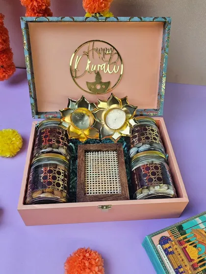 A glimpse into my Diwali collection. This festive hamper is curated with four jars of premium dry fruits, a decorative photo frame, and beautiful lotus-shaped diyas, all packed in an elegant pink wooden box with a 'Happy Diwali' acrylic cutout.