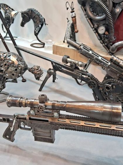 Intricate metal sculptures of guns and horses, showcasing the artist's skill in upcycling metal parts into detailed art.
