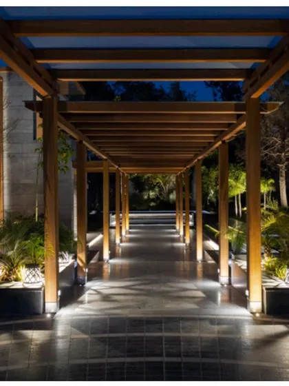 The pergola walkway lit up at night. The ground-level lighting creates a safe and visually stunning path, enhancing the connection between the different areas of the property.