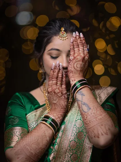 A creative portrait focusing on the bride's intricate henna design, with her face partially covered.