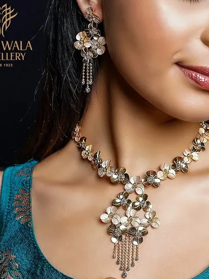 A model wears a stunning floral necklace and earring set crafted from two-tone gold, creating a rich and textured look.