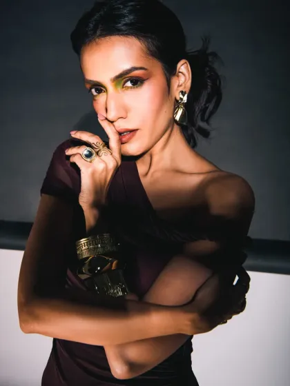 In this shot, the model's hand is brought close to her face, drawing attention to the statement ring and bracelets. The hard light creates a beautiful shine on the metal, contrasting with the shadows to create a bold, edgy look.