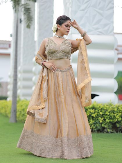 A model posing in a simple yet elegant gold lehenga, a versatile piece that can be dressed up or down for any festive occasion.