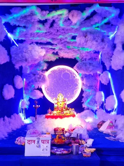 For a more creative Ganpati theme, I designed this celestial look. It features a deep blue backdrop with soft, cloud-like textures and a glowing moon behind the idol, all highlighted with cool blue LED strip lighting for a magical effect.