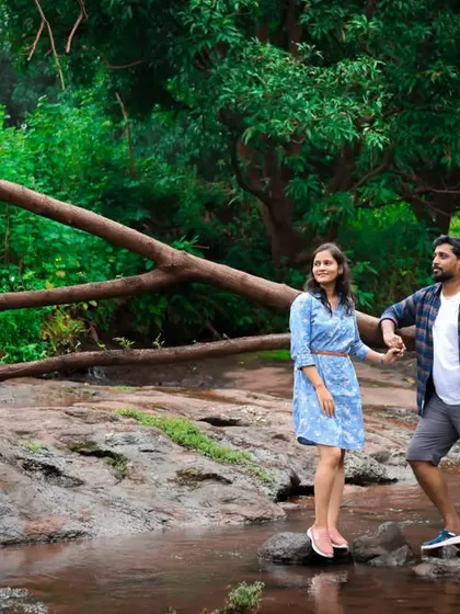 A candid pre-wedding photograph of a couple enjoying a serene moment by a stream in a lush green forest, perfect for couples who love the outdoors.