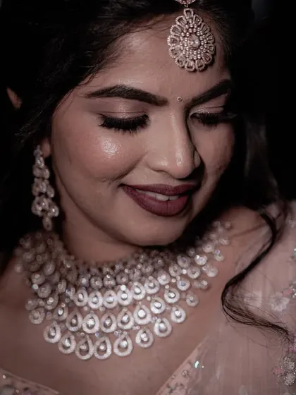 A detailed shot of the bride's diamond jewelry and soft makeup, showcasing her elegant reception look.