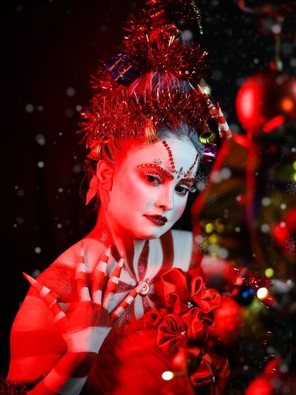 The dramatic red lighting enhances the festive mood of this Christmas makeup.